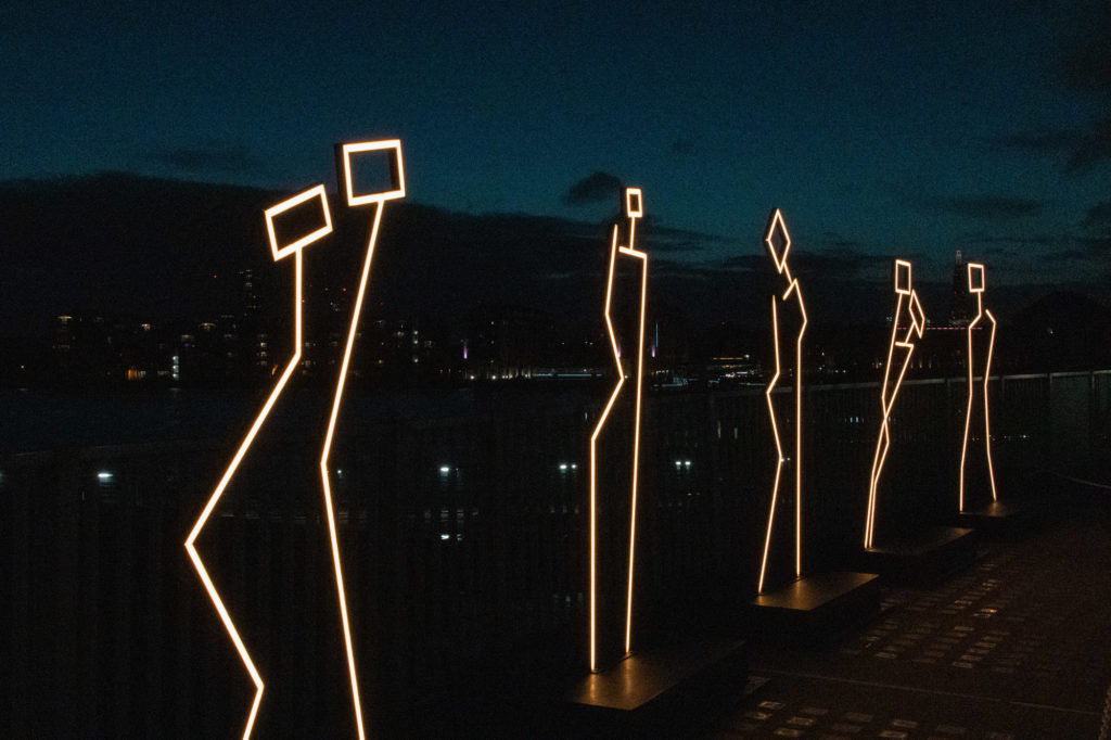 An iage of an art instalation of stylised figures against a shadowed sky. Image used to represent books catagorised as being sharp and searching.